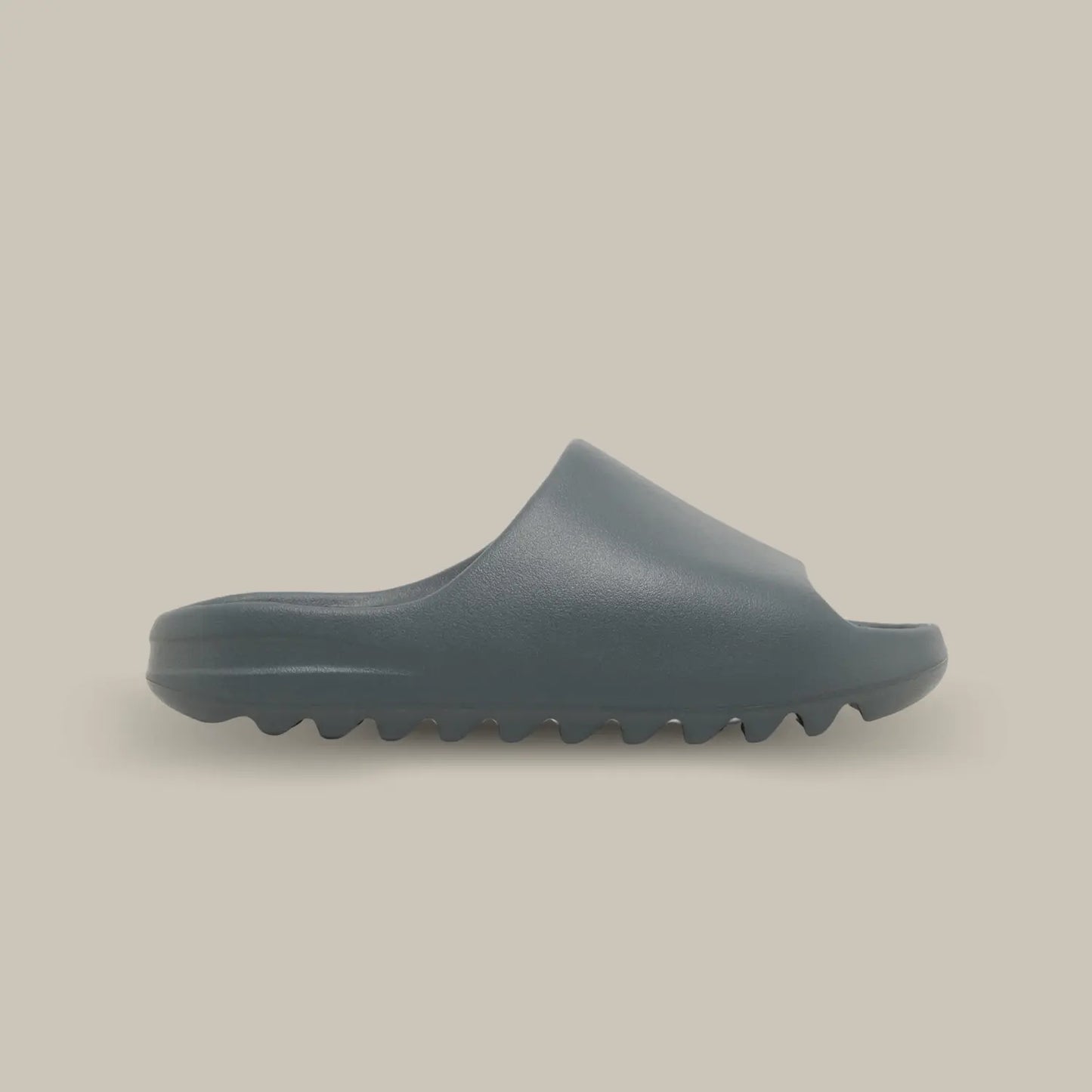 La Yeezy Slide "Slate Marine" de coté, cette claquette avec son coloris monochrome entre le gris et le bleu et sa semelle en mousse EVA.