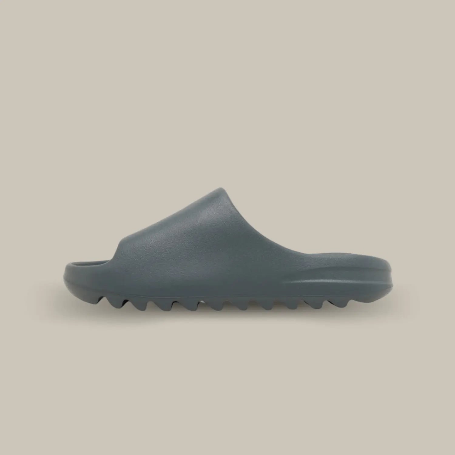 La Yeezy Slide "Slate Marine" de coté, cette claquette avec son coloris monochrome entre le gris et le bleu et sa semelle en mousse EVA.