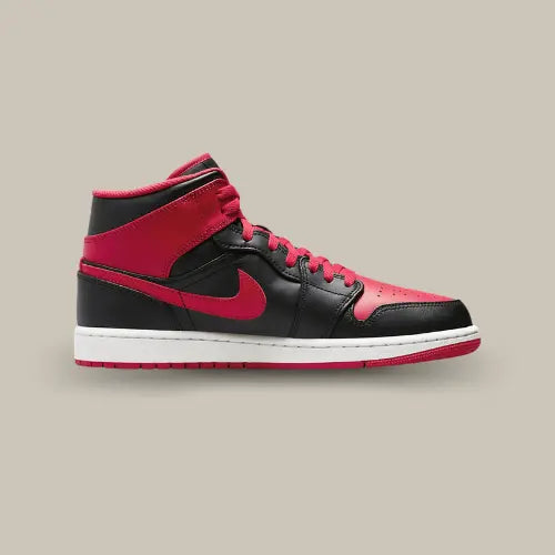 La Air Jordan 1 Mid Alternate Bred (2022) vue de côté avec son cuir noir et ses empiècements rouges au niveau de la toebox, du swoosh et des rabats.