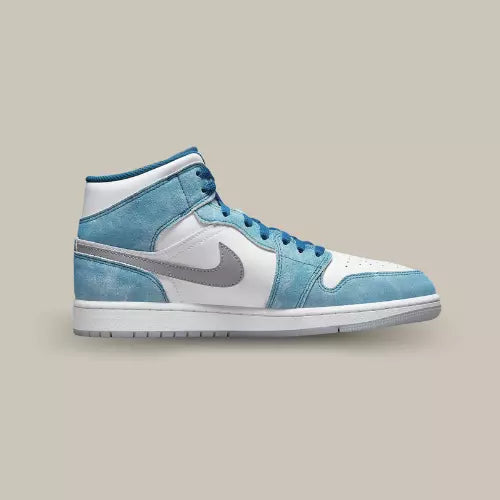La Air Jordan 1 Mid French Blue Fire Red de coté avec sa base en cuir blanc et ses empiècements en suède bleu clair.