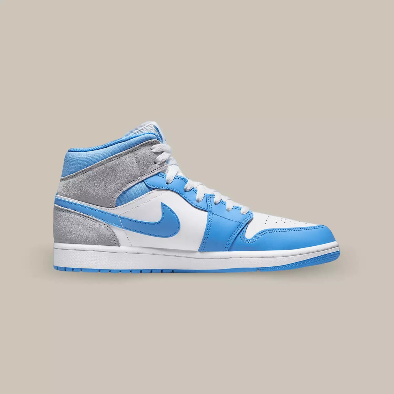 La Air Jordan 1 Mid University Blue Grey de coté avec son coloris UNC et une touche de suède gris qu’on retrouve à l’arrière de la sneakers.