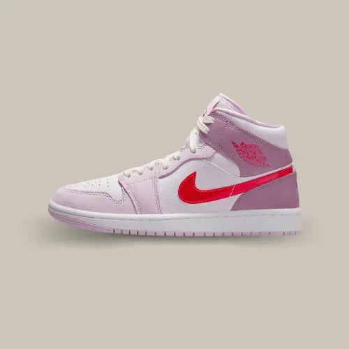 La Air Jordan 1 Mid Valentine's Day (2022) de côté avec sa base en cuir blanc, ses tons roses et son swoosh rouge accordé au logo Jordan.