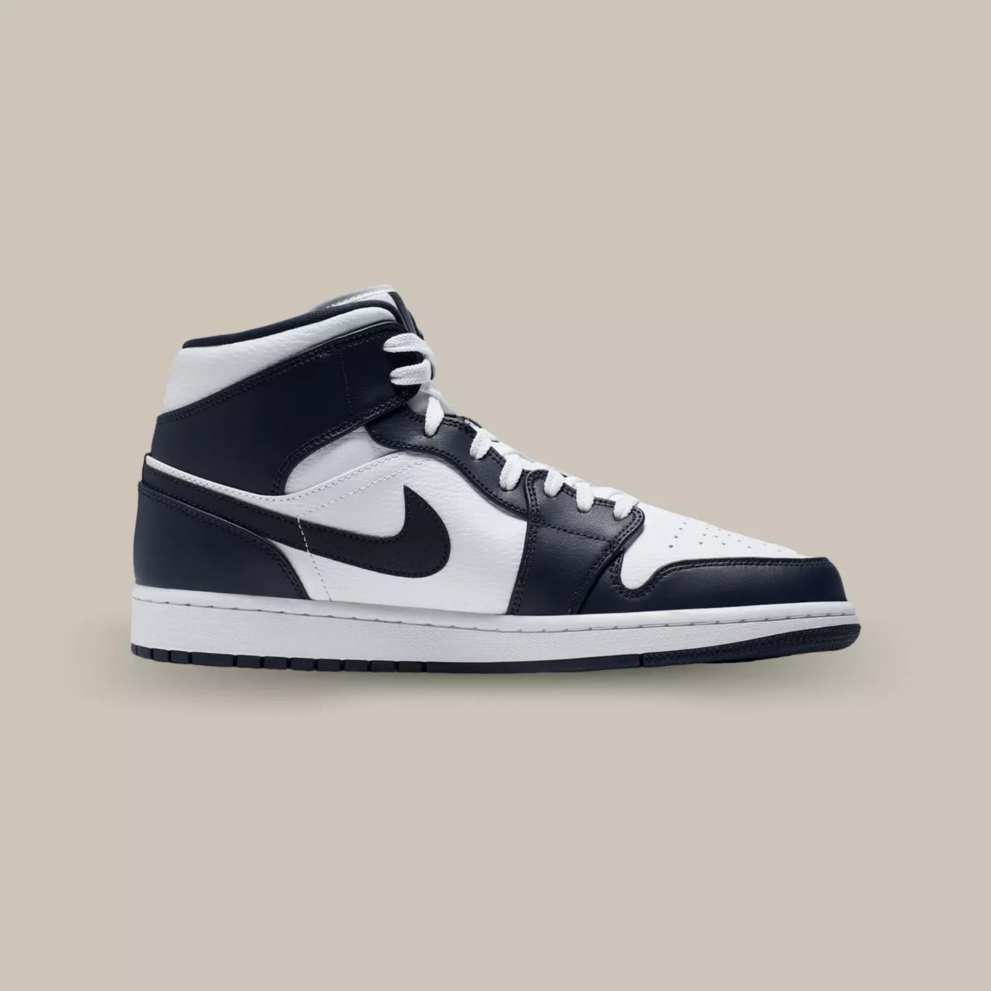 La Air Jordan 1 Mid White Metallic Gold Obsidian de coté avec sa base en cuir blanc sublimée par des superpositions en cuir d’un bleu très foncé, presque noir.
