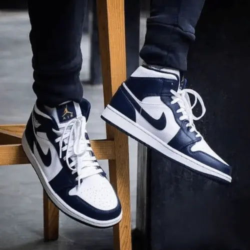 La Air Jordan 1 Mid White Metallic Gold Obsidian portée avec un jogging noir.
