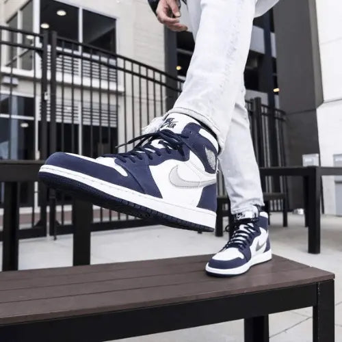 La Air Jordan 1 Retro High Midnight Navy (2020) portée avec un jean slim blanc.