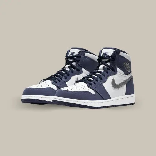 La Air Jordan 1 Retro High Midnight Navy (2020) possède une base de cuir blanc avec des empiècements en suède bleu navy et un swoosh gris métallisé accordé au swoosh. Tout cela est conclut par une semelle bicolore et le tag Nike Air brodé sur la languette.