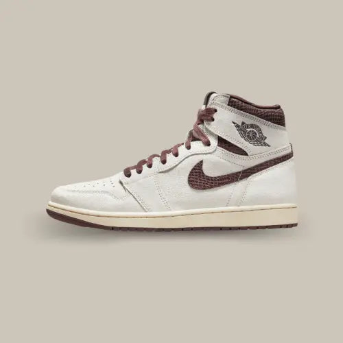 La Air Jordan 1 Retro High OG A Ma Maniére vue de côté avec sa base en cuir suédé blanc cassé et ses empiècements bordeaux en motif snakeskin.