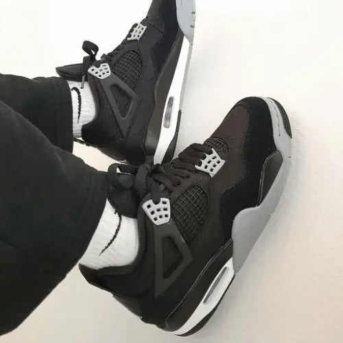 La Air Jordan 4 Black Canvas portée avec un pantalon noir évasé.