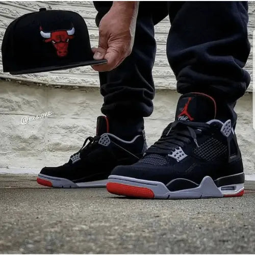 La Air Jordan 4 Retro Bred Reimagined portée avec un jogging noir.