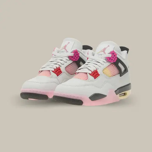 Paire de Air Jordan 4 Retro Comic vue de trois quarts avec base blanche, œillets colorés, mesh rose jaune et détails noirs. Disponible chez Offsneakz.