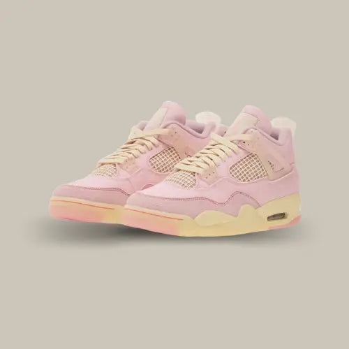Paire de Air Jordan 4 Retro Iced Carmine vue de trois quarts, avec empeigne rose poudré, lacets crème et détails pastel.