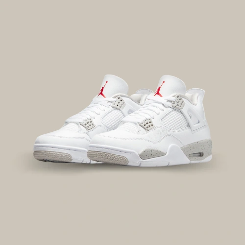 Paire de Air Jordan 4 Retro White Oreo 2021 blanche avec œillets Tech Grey mouchetés et Jumpman rouge, vue de trois quarts – disponible sur OFFSNEAKZ.