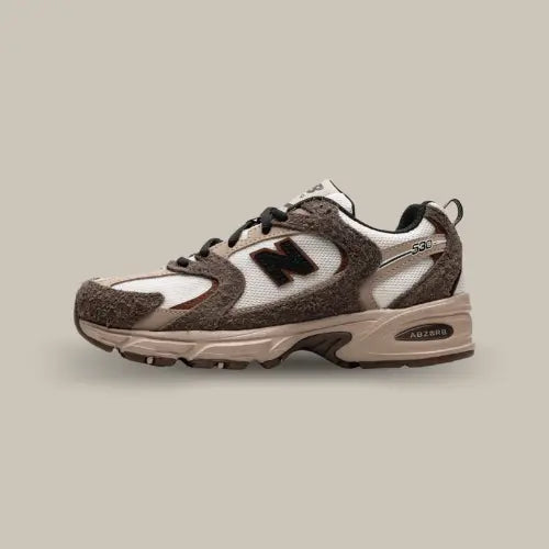 La New Balance 530 Brown Tan vue de côté avec sa base en cuir et mesh blanc et ses superpositions de couleurs marrons.