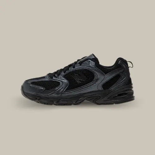 La New Balance 530 Triple Black Leather avec sa base full black et ses empiècements ton sur ton.