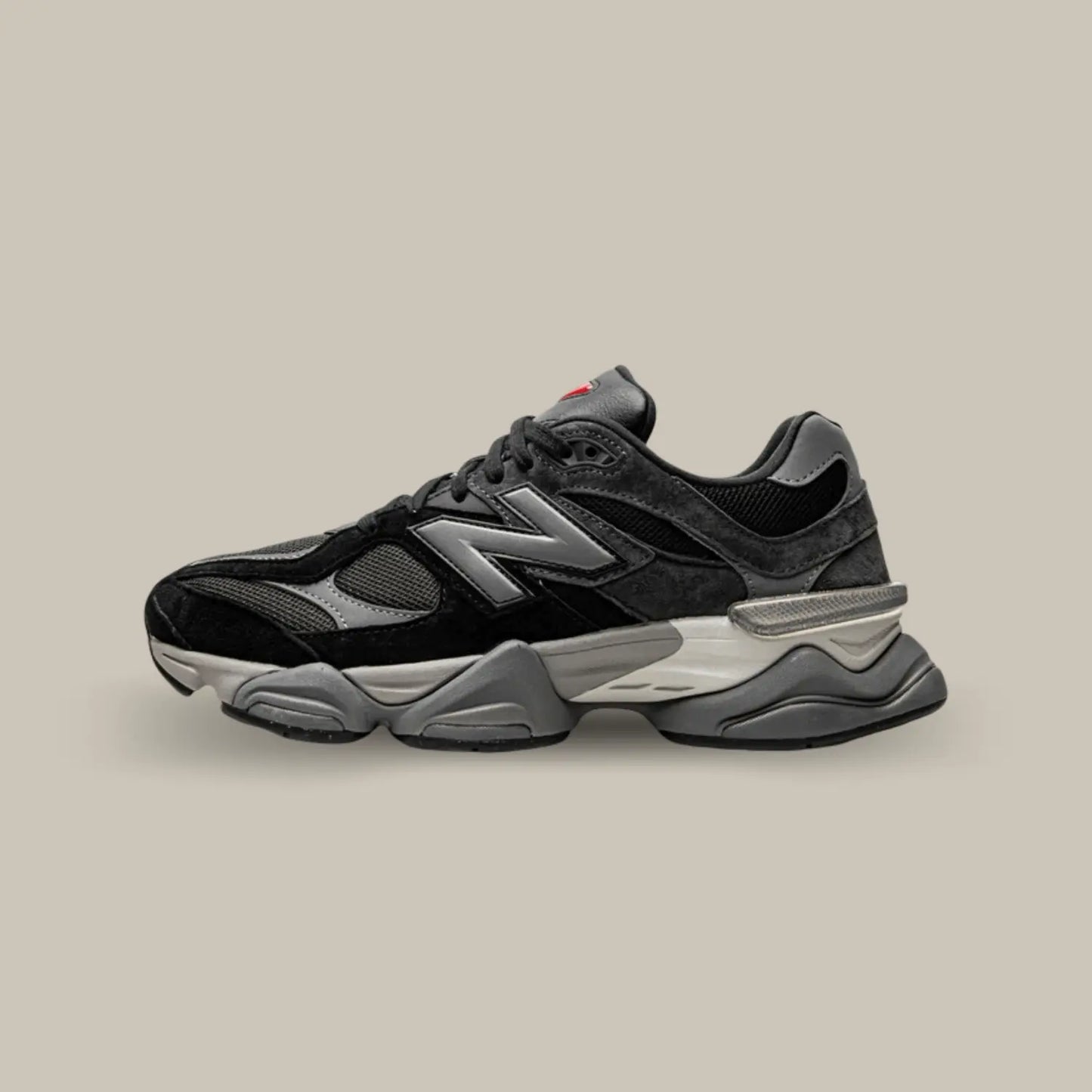 La New Balance 9060 Black Castlerock de coté avec une base en mesh gris accompagnée de superpositions en cuir gris sur l’arrière du modèle et en daim noir sur l’avant.