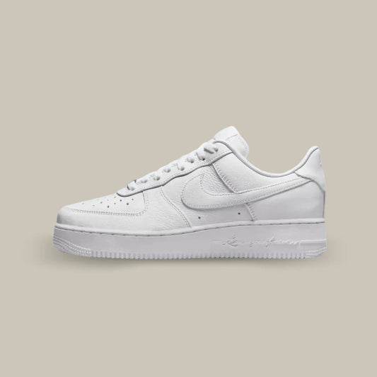 La Nike Air Force 1 NOCTA de coté avec sa base en cuir blanc et le "AIR" de la semelle remplacée par "Love you forever".