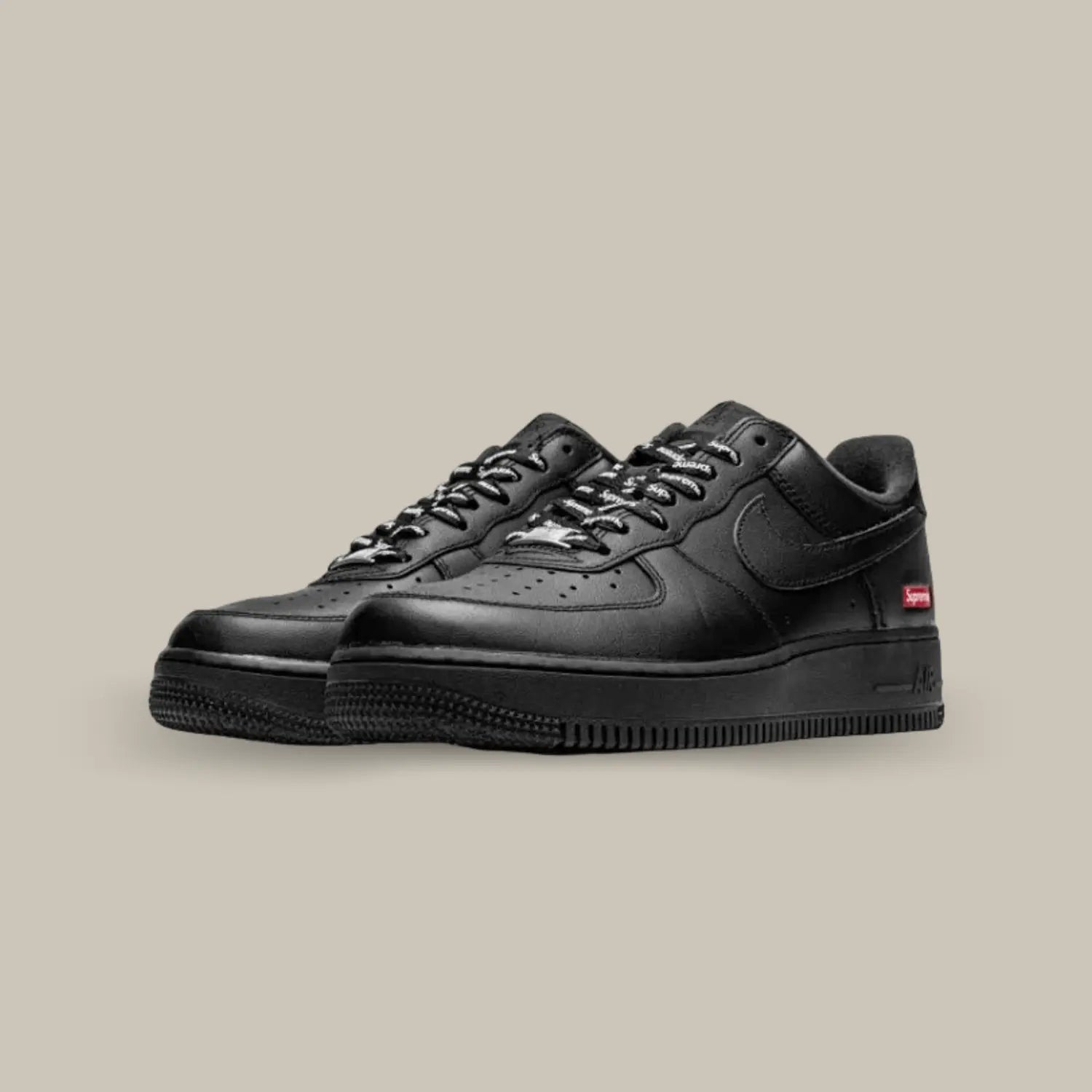 On retrouve une Nike Air Force 1 Black Supreme avec son classique cuir noir et la petite touche Supreme avec le logo sur fond rouge.