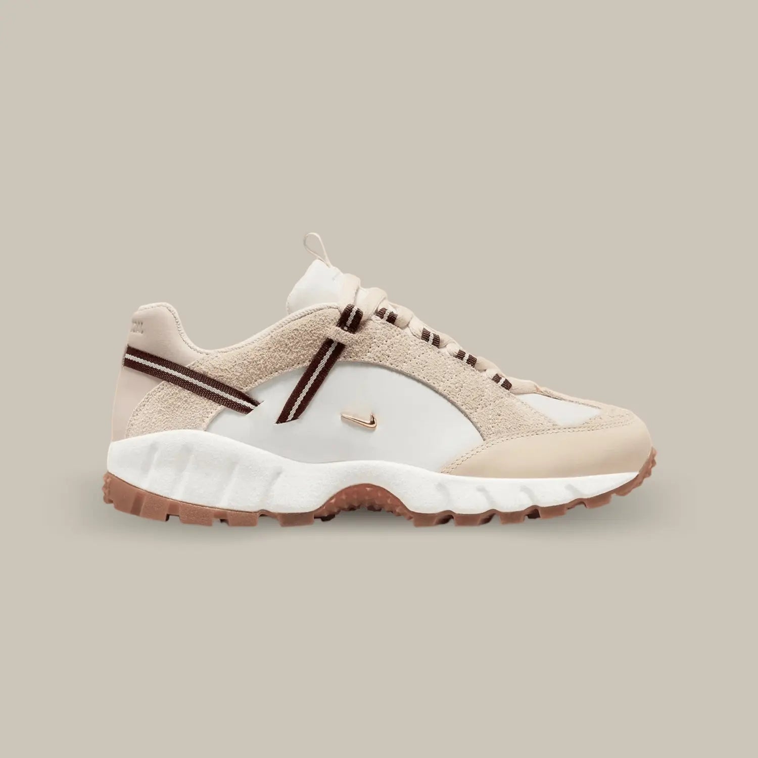 La ike Air Humara LX Jacquemus Beige de coté avec une base en cuir lisse blanc avec deux petit swoosh doré représentatif de la collaboration avec Jacquemus. On retrouve du cuir et du suède crème et une sangle qui accompagne les lacets.