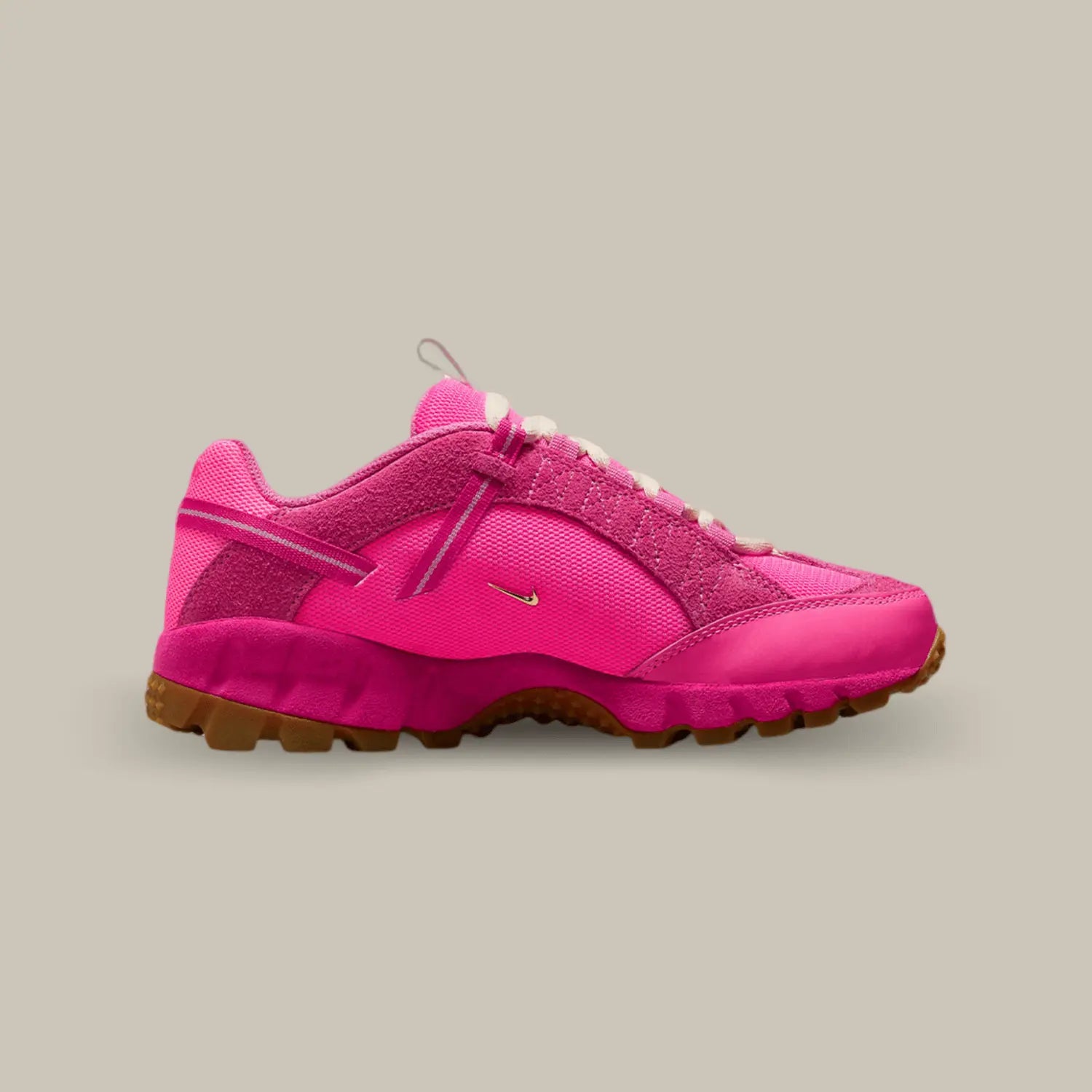 La Nike Air Humara LX Jacquemus Rose de coté avec une base en mesh rose et deux petit swoosh doré représentatif de la collaboration avec Jacquemus. On retrouve du cuir et du suède ton-sur-ton et une sangle qui accompagne les lacets.