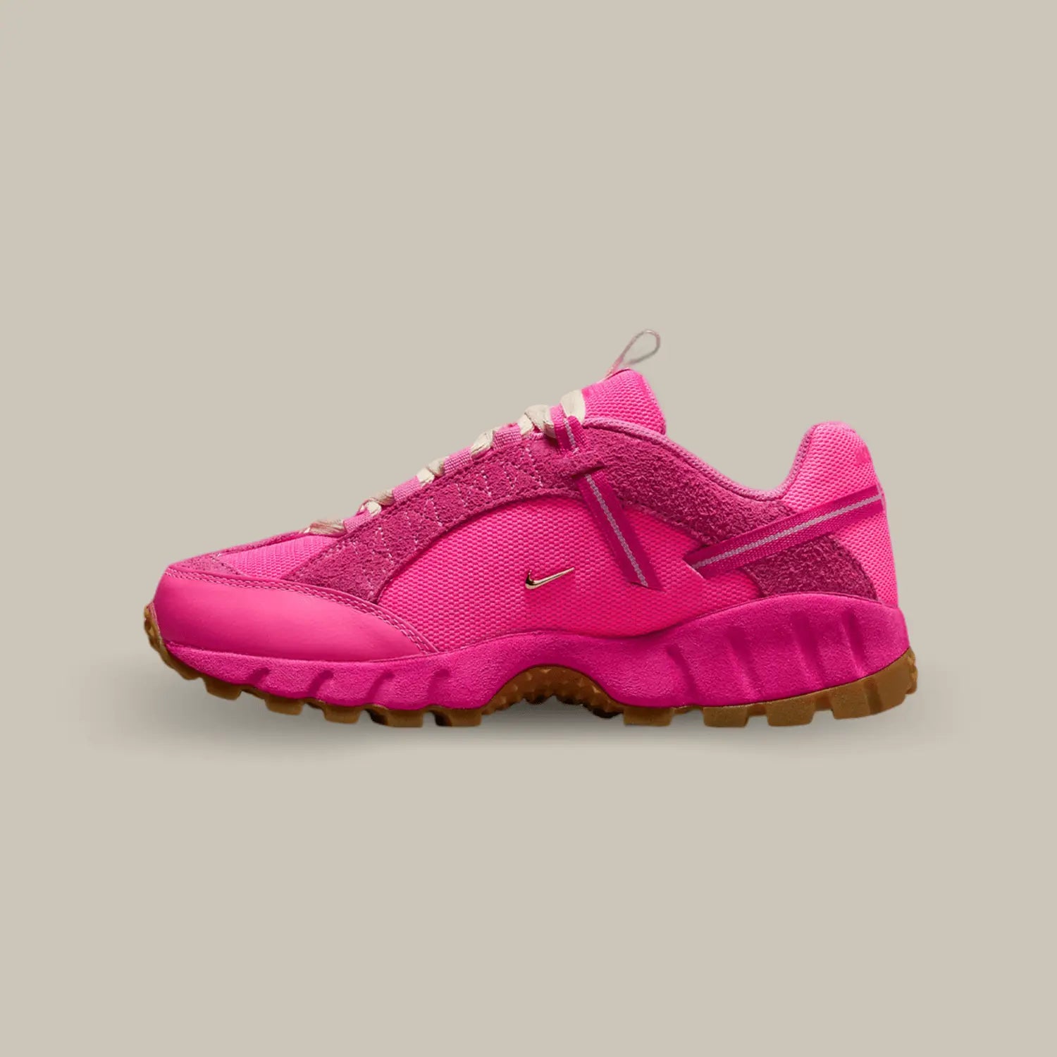 La Nike Air Humara LX Jacquemus Rose de coté avec une base en mesh rose et deux petit swoosh doré représentatif de la collaboration avec Jacquemus. On retrouve du cuir et du suède ton-sur-ton et une sangle qui accompagne les lacets.