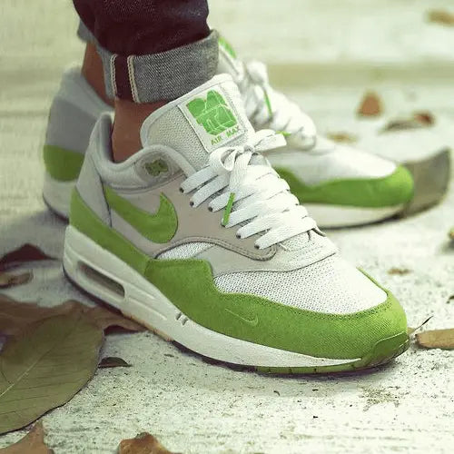 La Nike Air Max 1 Patta Chlorophyll (2024) portée avec un jean bleu foncé possédant un ourlet.