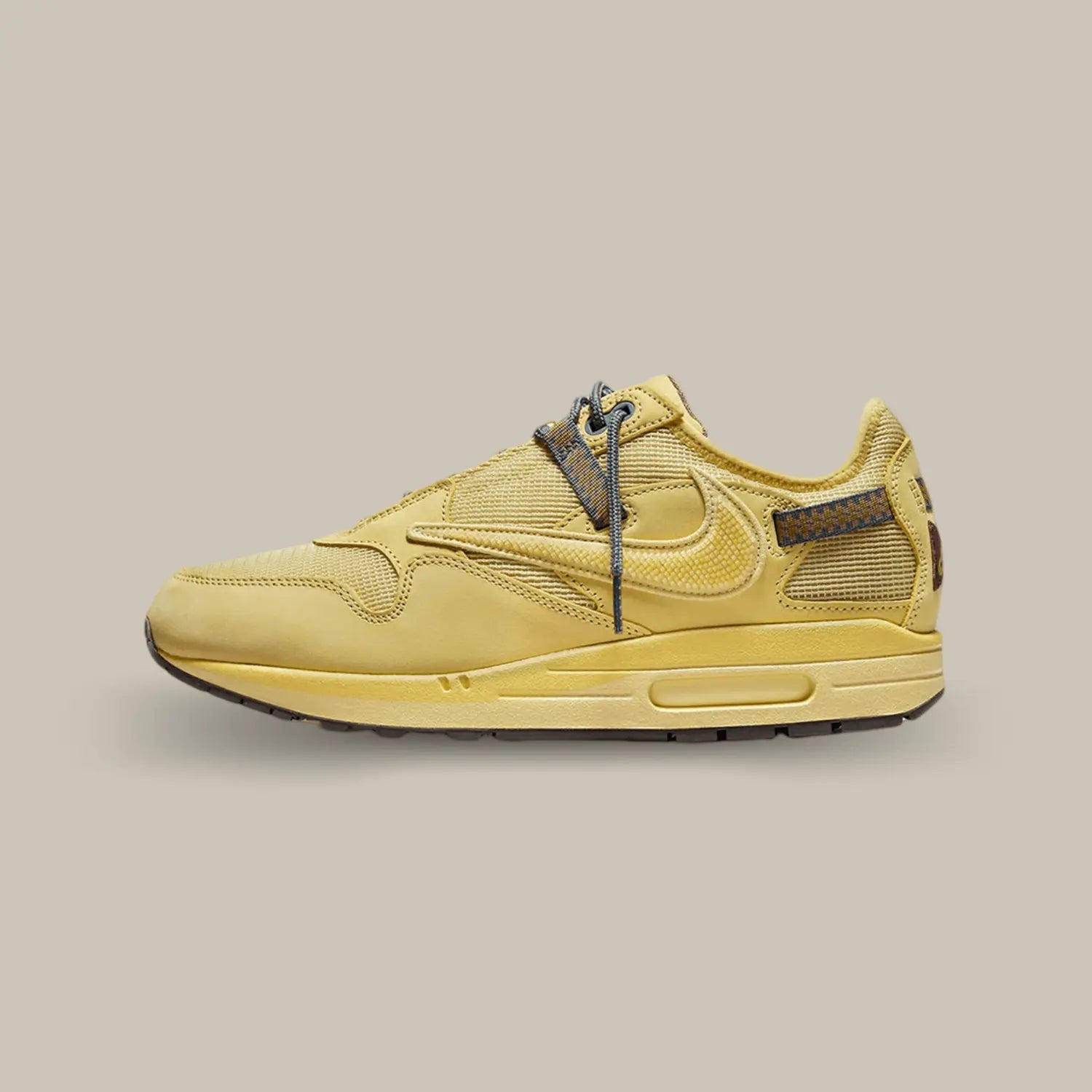 La Nike Air Max 1 Travis Scott Cactus Jack Saturn Gold de coté avec une base en mesh jaune « Wheat » et différents empiècements de la même couleur en daim. On retrouve le swoosh inversé qui a fait le succès de la collaboration entre Nike et Cactus Jack. On trouve un branding Cactus Jack sur le talon et la languette.