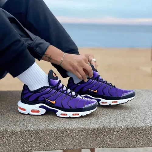 La Nike Air Max Plus Voltage Purple portée avec un pantalon noir et des chaussettes blanches.