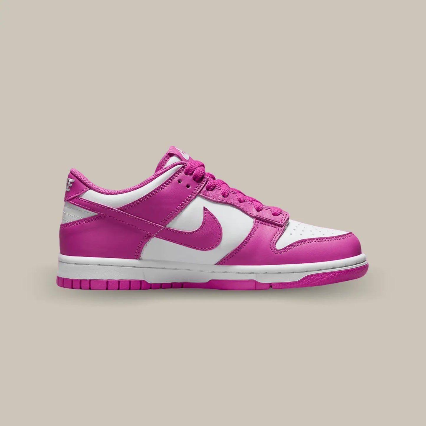 La Nike Dunk Low Active Fuschia de coté avec sa tige en cuir blanc aux superpositions de cuir rose fuchsia. Des lacets assortis se posent sur une languette blanche.