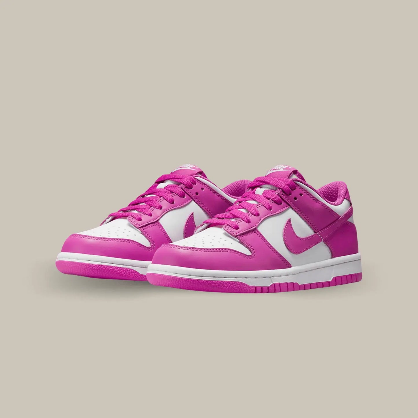 La Nike Dunk Low Active Fuschia présente une tige en cuir blanc aux superpositions de cuir rose fuchsia. Des lacets assortis se posent sur une languette blanche.