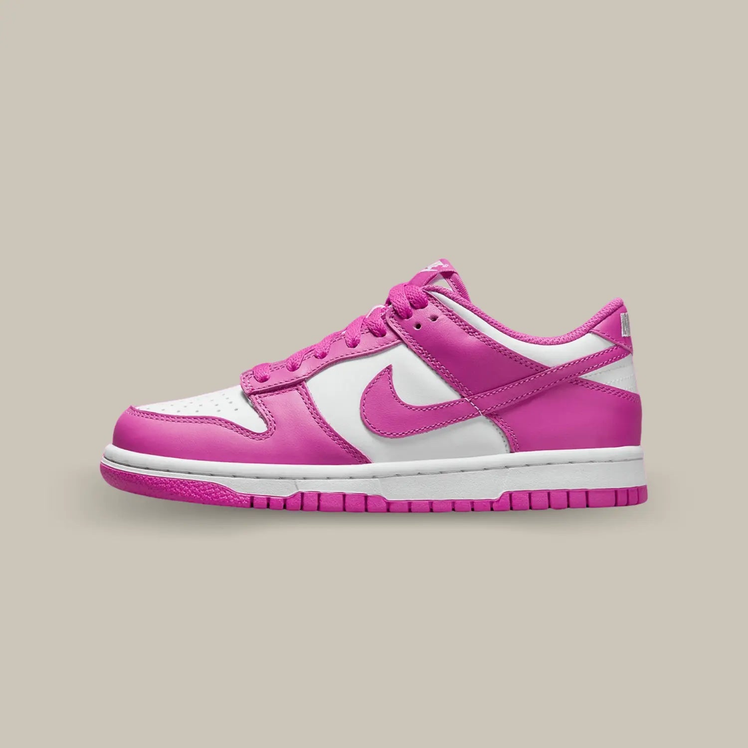 La Nike Dunk Low Active Fuschia de coté avec sa tige en cuir blanc aux superpositions de cuir rose fuchsia. Des lacets assortis se posent sur une languette blanche.