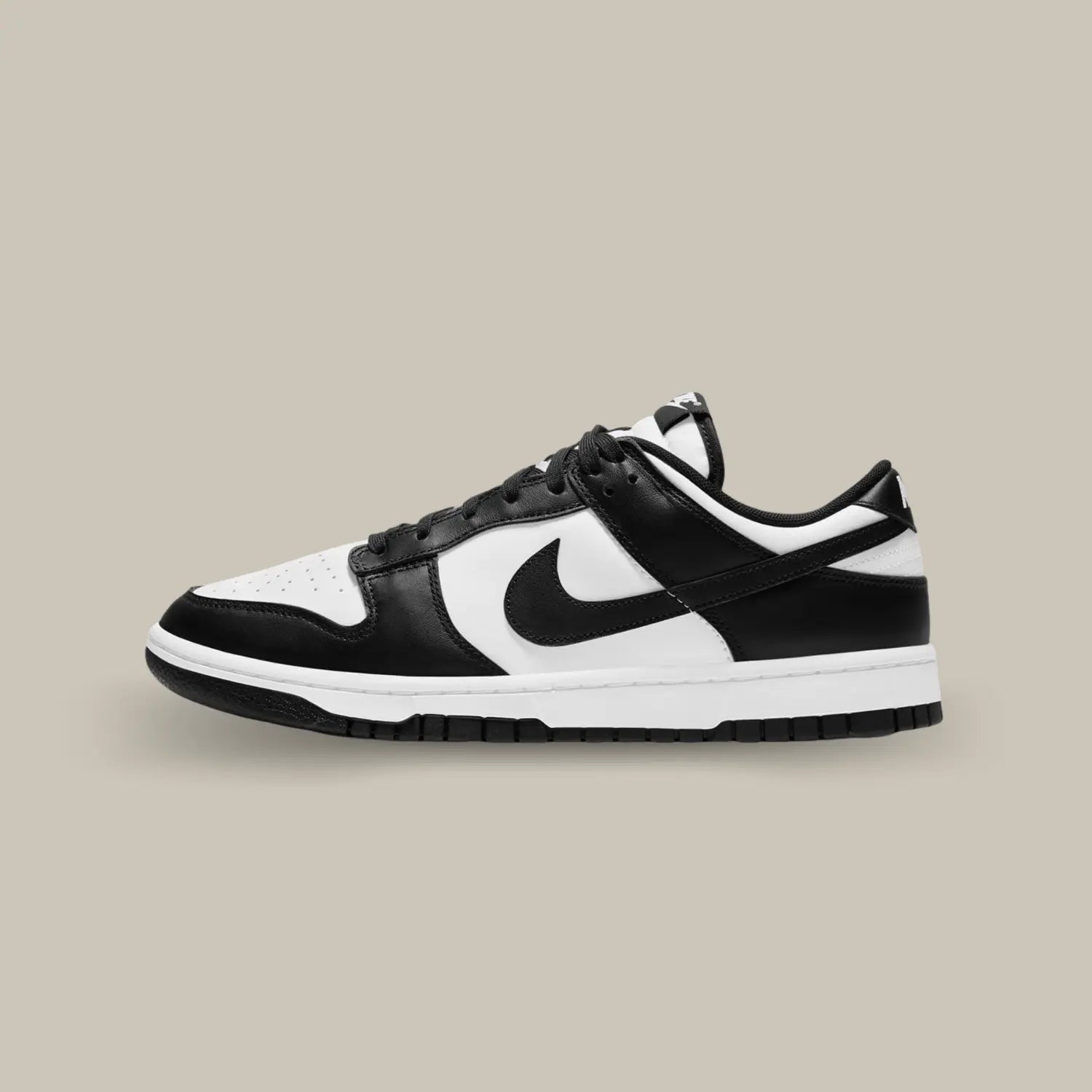 La Nike Dunk Low Black White de coté avec sa tige en cuir blanc, rehaussée par des empiècements en cuir noir pour un contraste tout en sobriété.