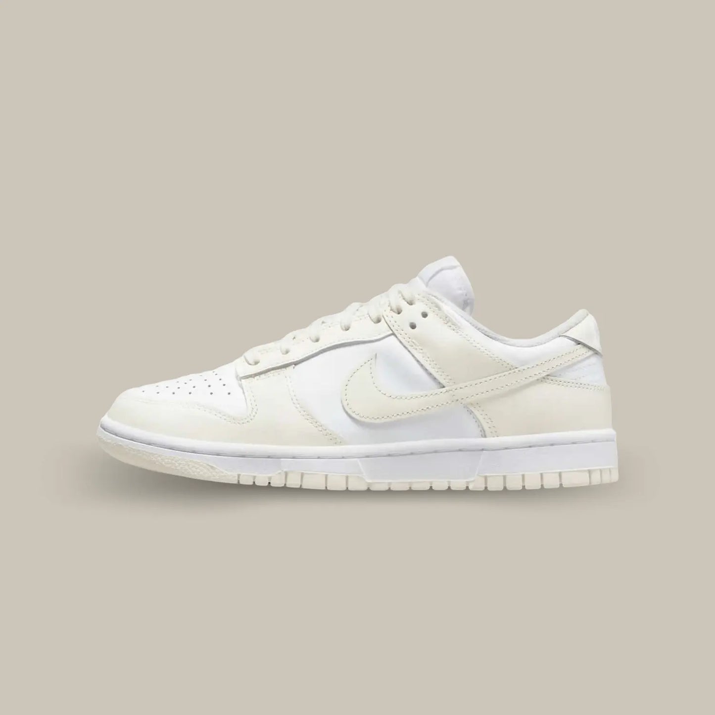 La Nike Dunk Low Coconut Milk de coté avec sa base en cuir blanc cassé, surélevée par des empiècements en cuir beige pastel.