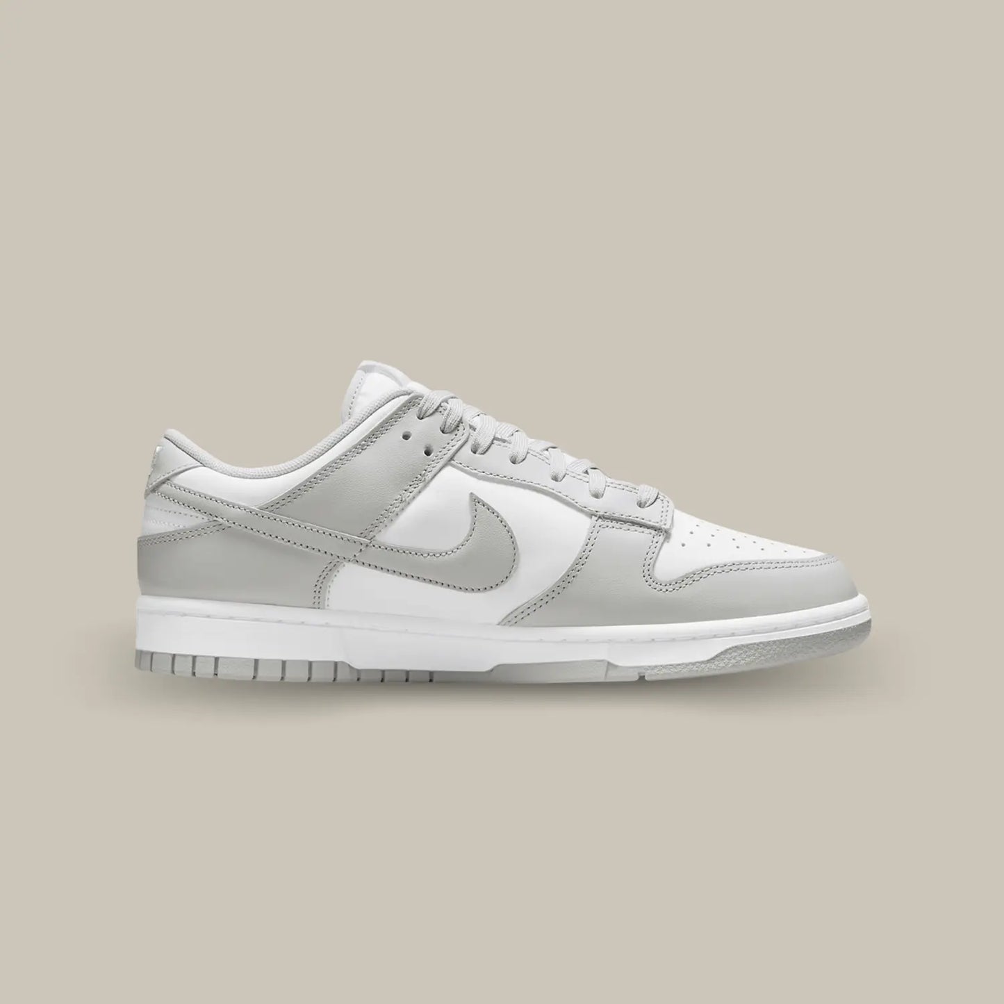 La Nike Dunk Low Grey Fog de coté avec son empeigne en cuir blanc, relevée d’empiècements en cuir gris clair.