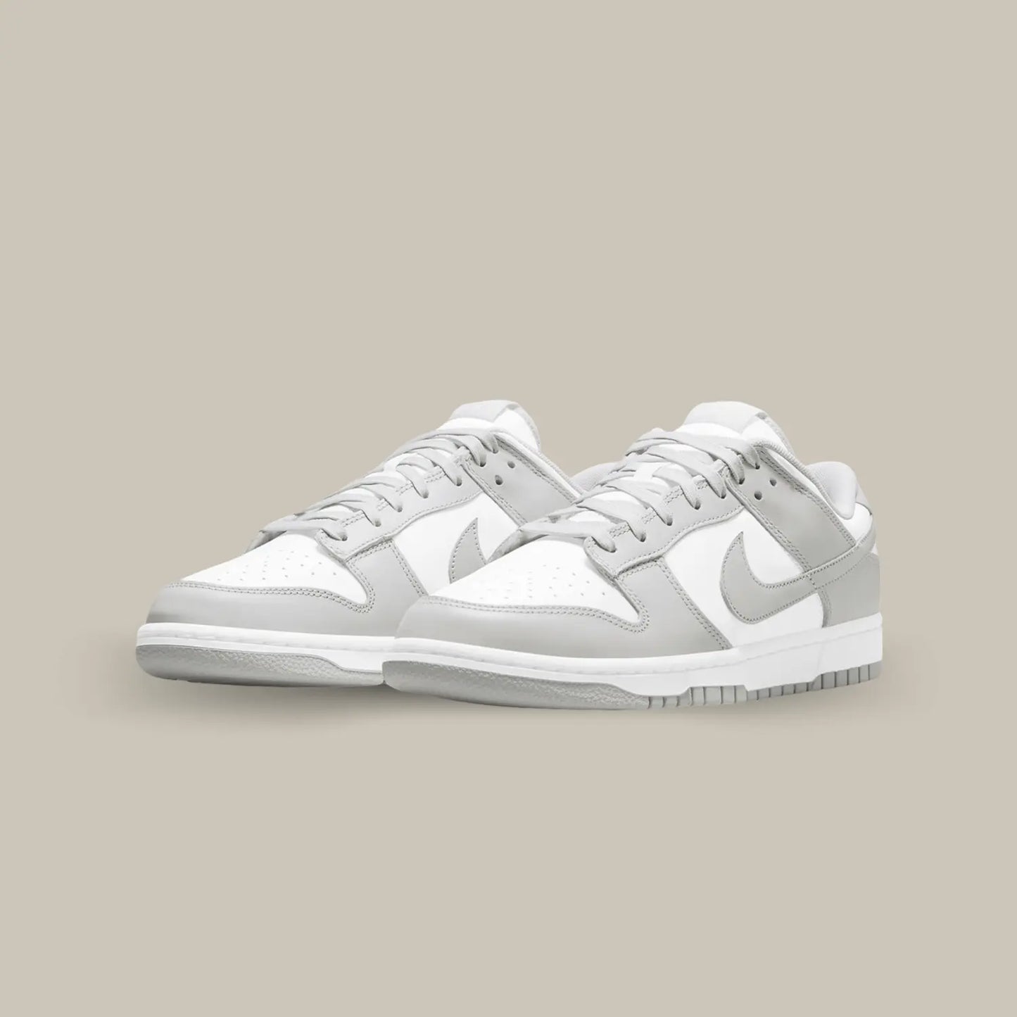 La Nike Dunk Low Grey Fog affiche l’habituelle empeigne en cuir blanc, relevée d’empiècements en cuir gris clair.