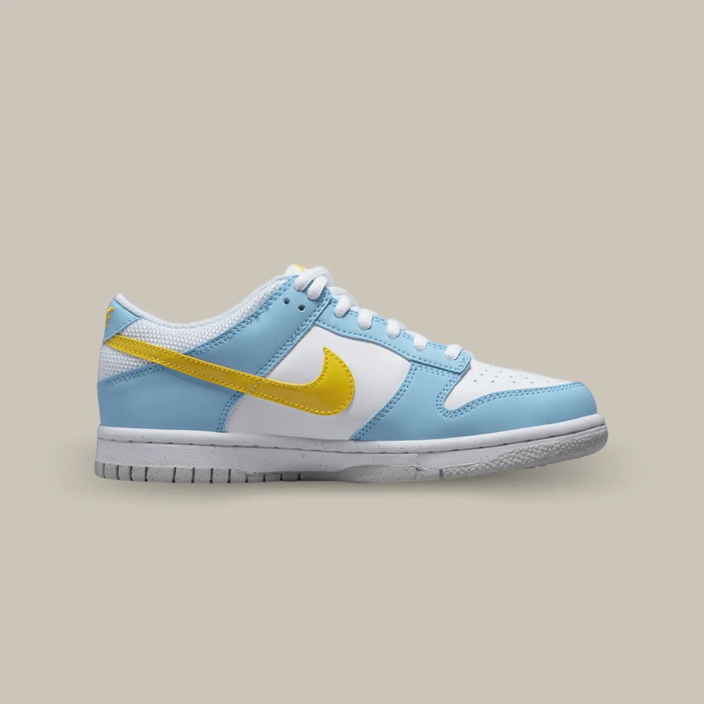 La Nike Dunk Low Homer Simpson de coté avec une base blanche, des empiècements bleu clair et un swoosh jaune à l'image de Homer Simpson.