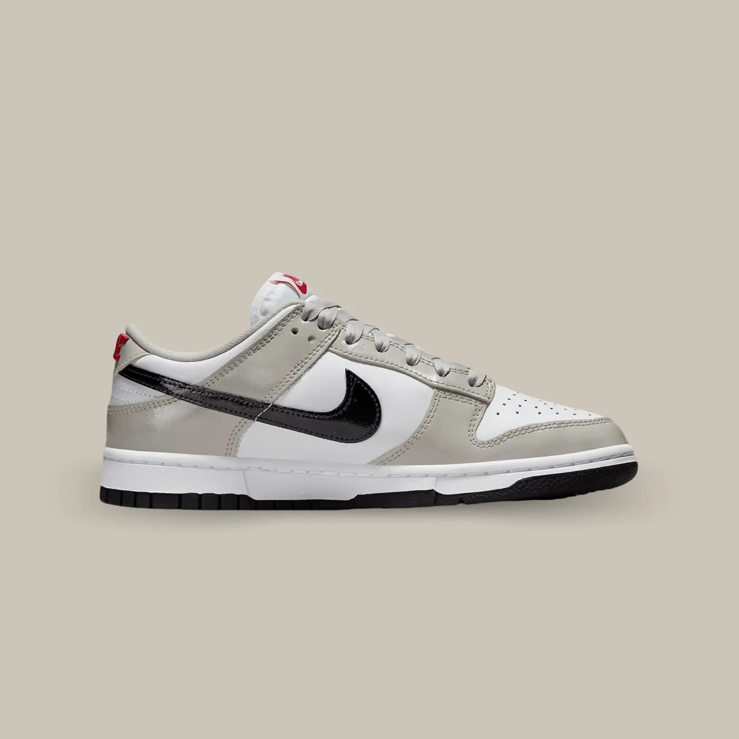 La Nike Dunk Low Light Iron Ore Black de coté avec une base en cuir blanc surmontée d’empiècements en cuir gris et d’un Swoosh latéral noir en cuir verni.