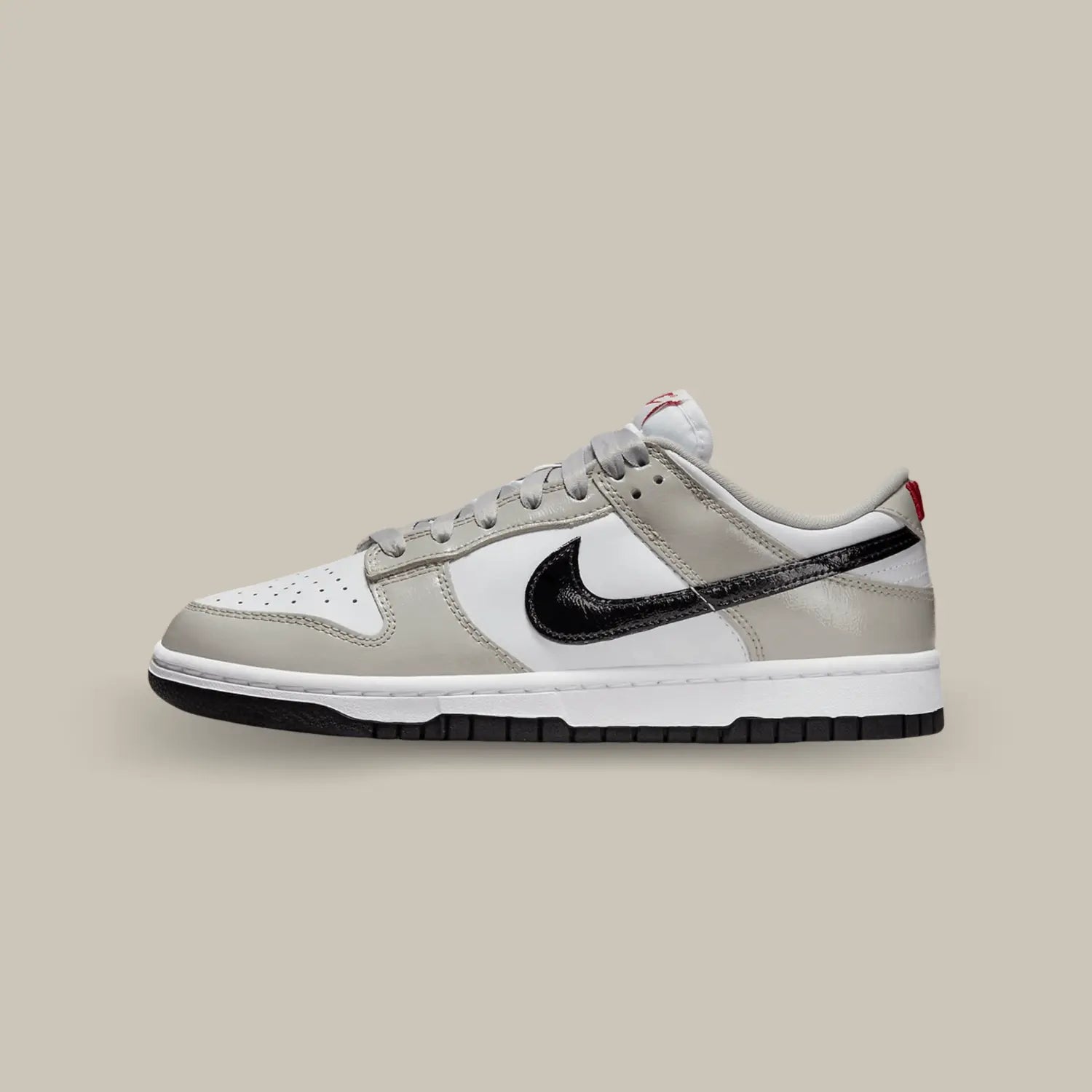 La Nike Dunk Low Light Iron Ore Black de coté avec une base en cuir blanc surmontée d’empiècements en cuir gris et d’un Swoosh latéral noir en cuir verni.