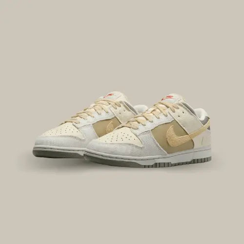 La Nike Dunk Low Light Bone Dark Stucco possède une base en cuir taupe avec des empiècements en tissu beige, blanc cassé et coconut milk. Le swoosh en daim jaune s'accorde aux lacets et complète magnifiquement cette paire.
