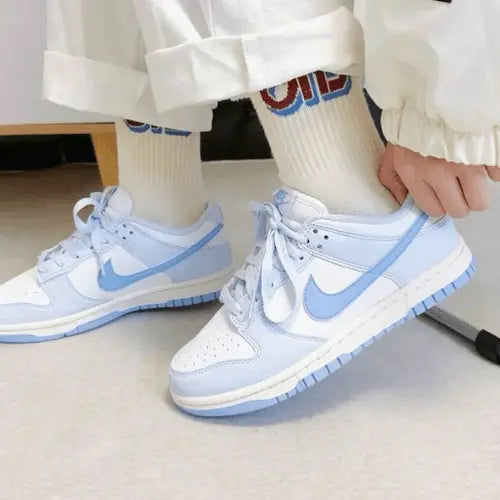 La Nike Dunk Low Next Nature Blue Tint portée avec un pantalon blanc.