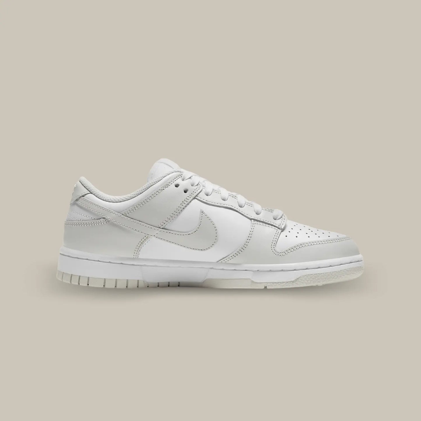 La Nike Dunk Low Photon Dust de coté avec sa base de cuir blanc pourvue d’empiècements en cuir gris.