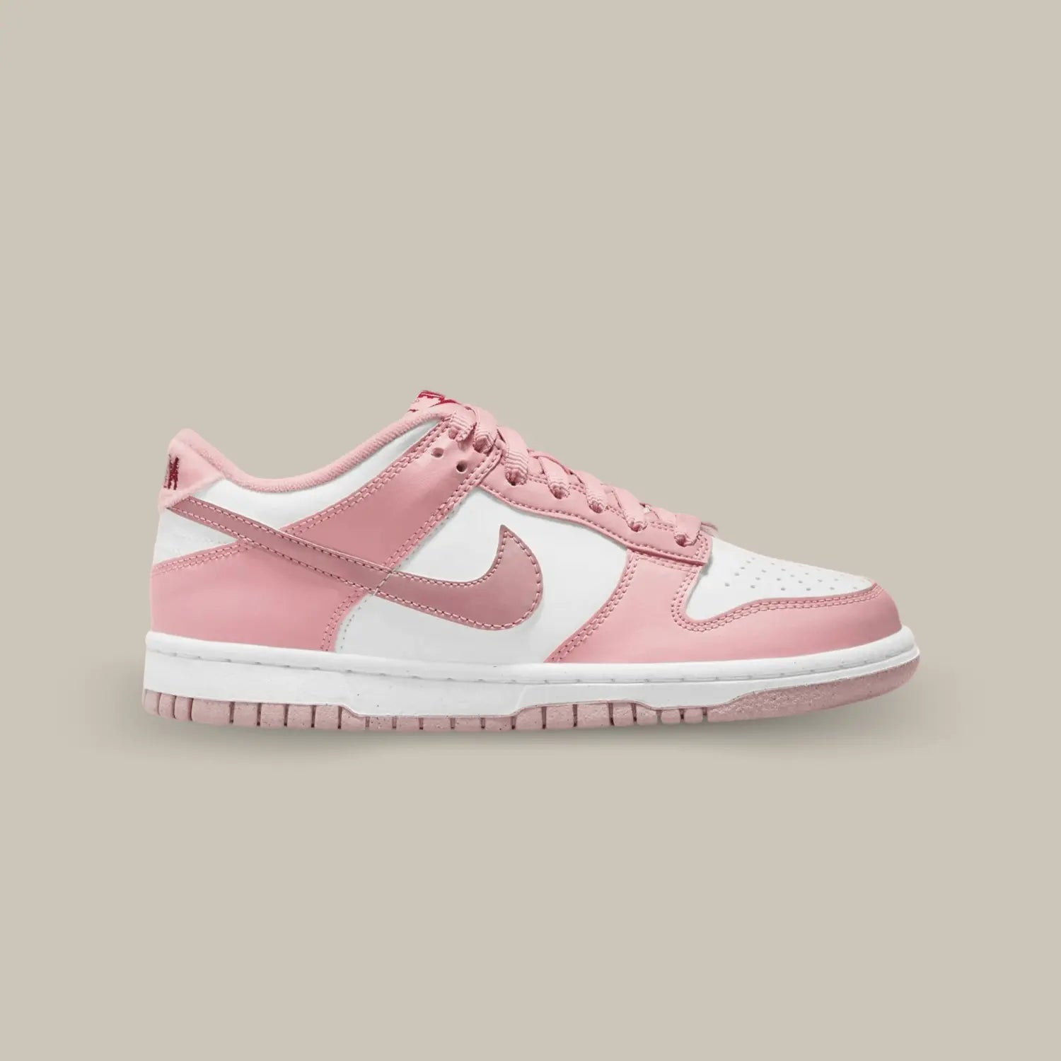 La Nike Dunk Low Pink Velvet de coté avec une empeigne en cuir lisse blanc, couplée à superpositions en cuir rose clair.