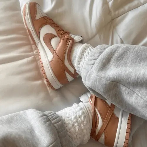 La Nike Dunk Low Rose Whisper portée avec un jogging gris et des chaussettes épaisses blanches.