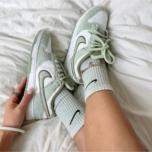 La Nike Dunk Low SE Fleece Green portée avec une paire de chaussette Nike blanche.