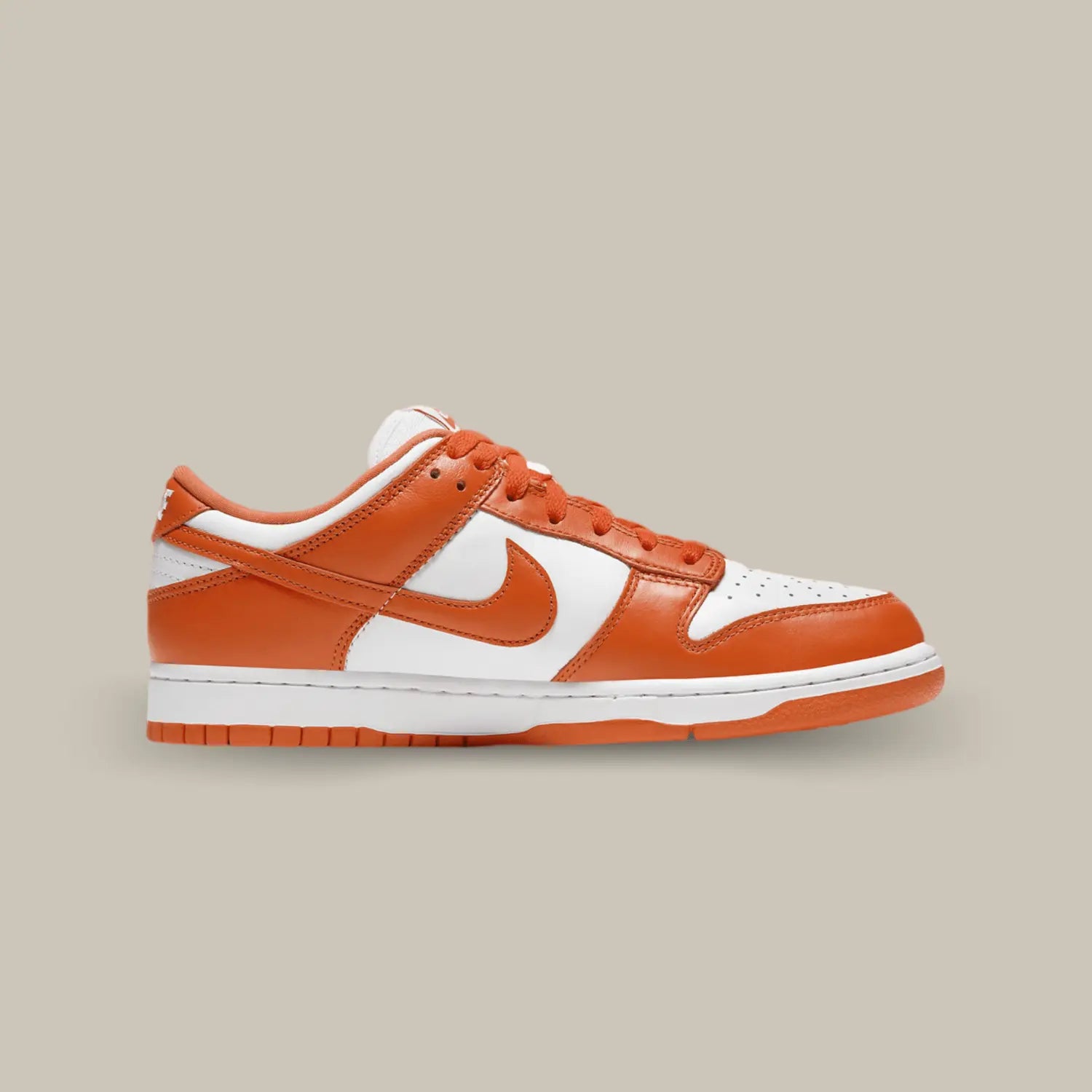 La Nike Dunk Low Syracuse de coté avec une base en cuir blanc et des empiècements orange.