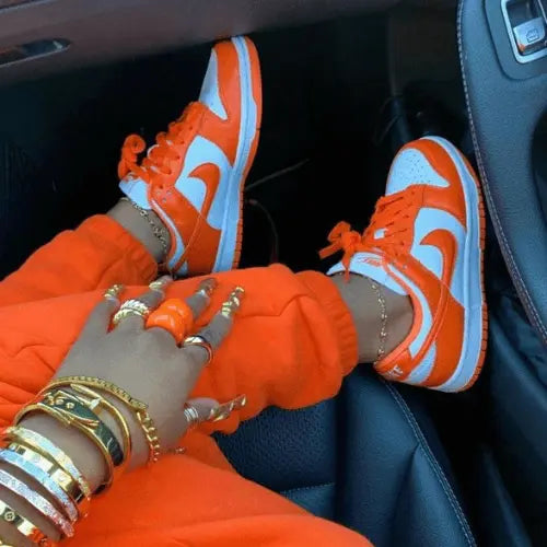 La Nike Dunk Low Syracuse portée avec un jogging orange.