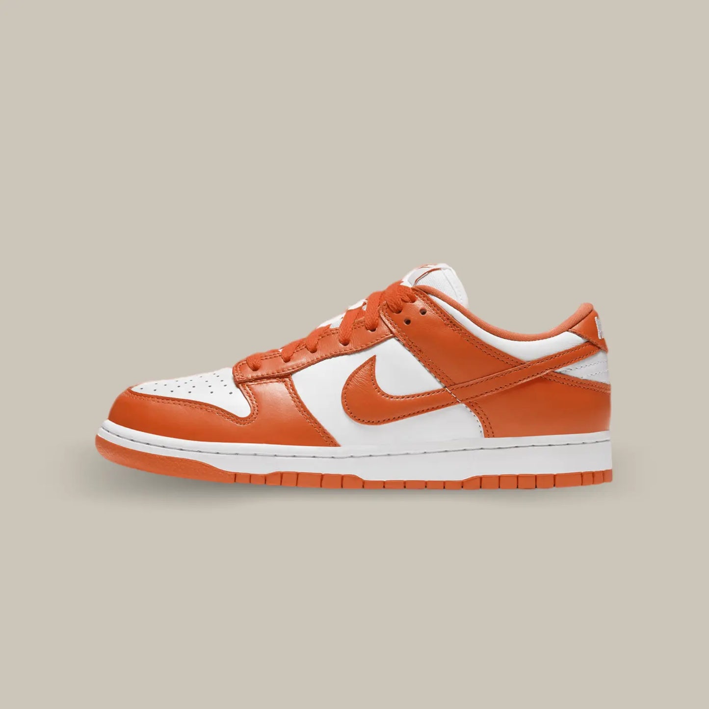 La Nike Dunk Low Syracuse de coté avec une base en cuir blanc et des empiècements orange.