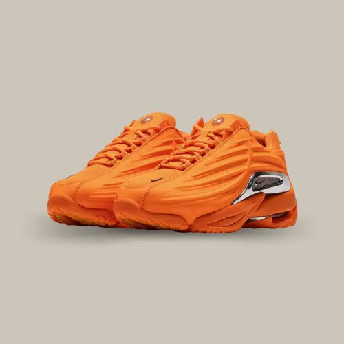 La Nike Hot Step 2 NOCTA Total Orange possède une base en mesh et en cuir orange et des détails ondulés tout le long de la paire. On retrouve l'unité Air au niveau du talon et une plaque réfléchissante avec un mini swoosh nike sur le côté qui accentue l'aspect futuriste de la petite dernière de la collection NOCTA.