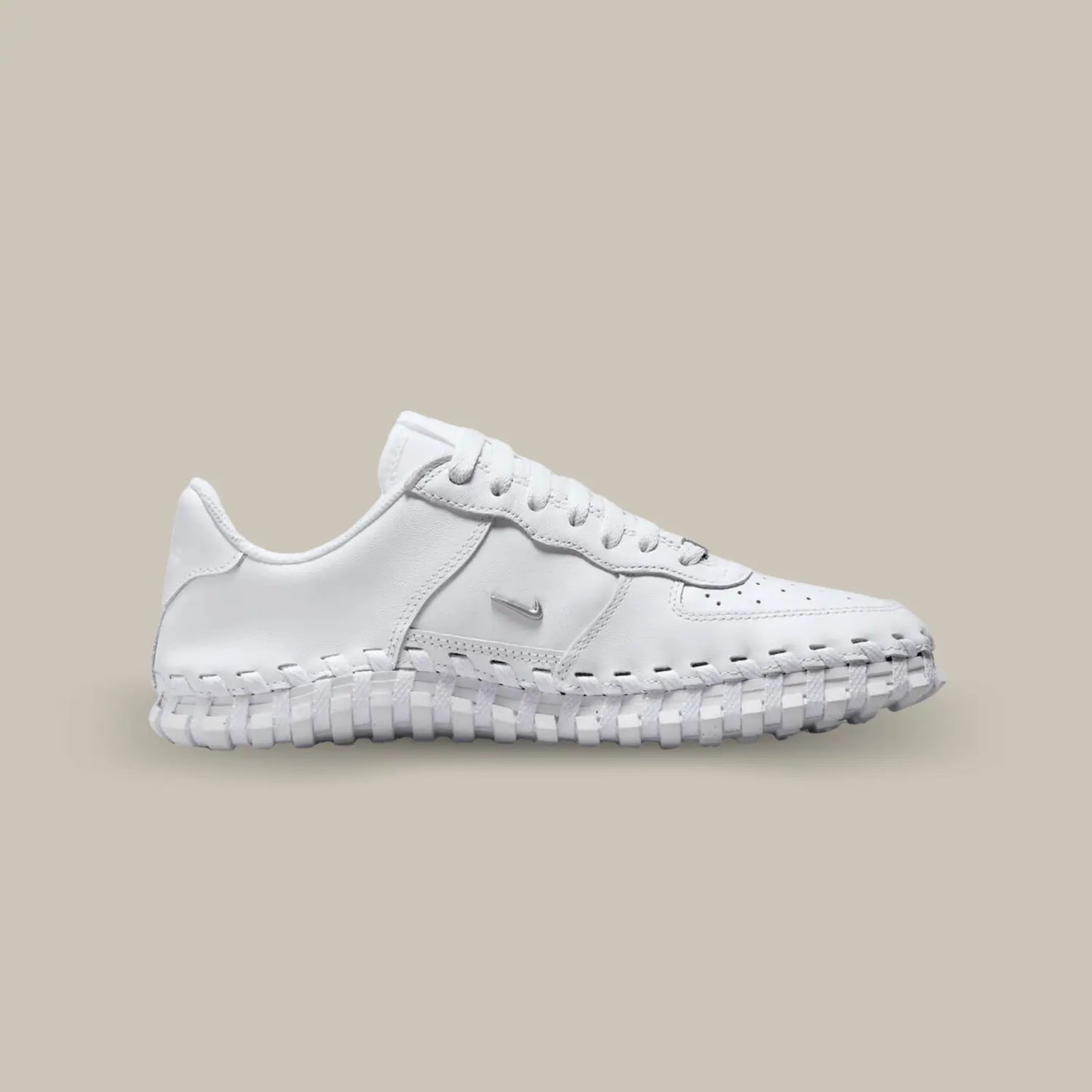 La Nike J Force 1 Low Jacquemus White de coté avec une base en cuir blanc et en mesh accompagnée d’une semelle tressée.