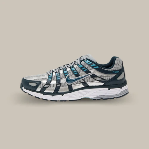 Nike P-6000 Armory Navy bleu marine, argentée et turquoise avec Swoosh métallisé, vue de profil sur fond beige. Disponible sur Offsneakz.