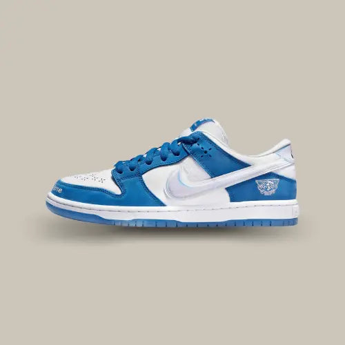 La Nike SB Dunk Low Born x Raised One Block At A Time de coté avec sa couleur blanche et bleu royal et son swoosh holographique.